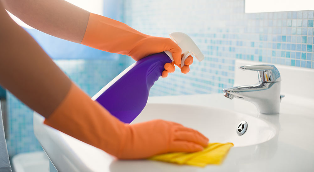 spraying a bathroom sink with cleaner